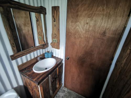 Un baño con lavabo y puerta de madera. en Cabaña Canto del Zorzal, en Villarrica