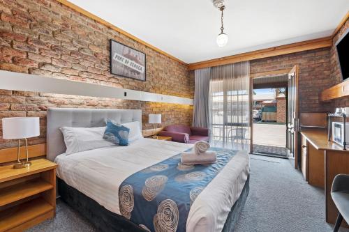 a bedroom with a bed and a brick wall at The Settlement Historic Hotel in Echuca