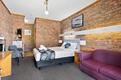 a hotel room with a bed and a couch at The Settlement Historic Hotel in Echuca