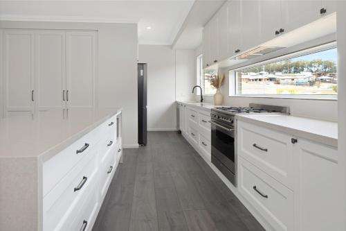 een keuken met witte kasten en een groot raam bij 4 bedroom home with theatre room, close to CBD and beaches. in Sunshine Bay