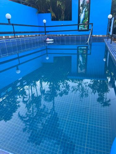 a blue swimming pool with palm trees in the water at ARABIAN HOLIDAY RESORT WITH SWIMMING POOL IN IDUKKI Calvary Mount in Idukki