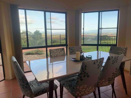 a dining room with a table and chairs and windows at A picturesque 3 bedroom house with splendid views in Atherton