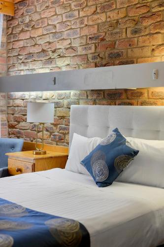 a bedroom with a bed and a brick wall at The Settlement Historic Hotel in Echuca