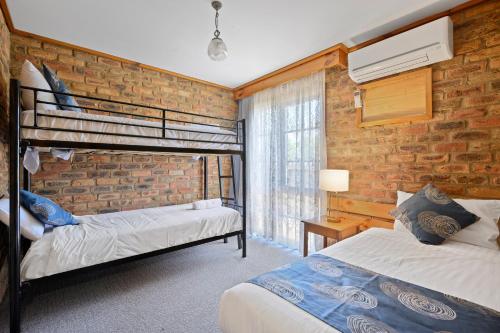 a bedroom with two bunk beds and a brick wall at The Settlement Historic Hotel in Echuca