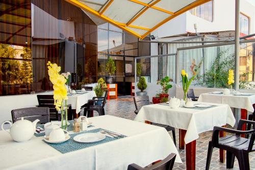 un restaurante con mesas blancas y sillas con flores amarillas en Hotel Plaza San Antonio Arequipa, en Arequipa