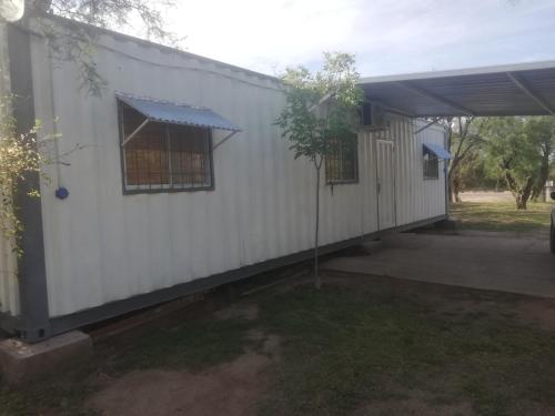 a side view of a white building with a garage at container in San Gerónimo