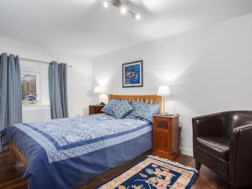 a bedroom with a bed with a blue comforter and a chair at Fieldview - Uk40947 in Auchtermuchty