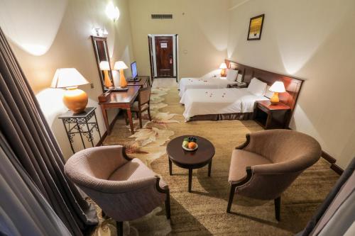 a hotel room with a bed and two chairs at Saigon Quy Nhon Hotel in Quy Nhon