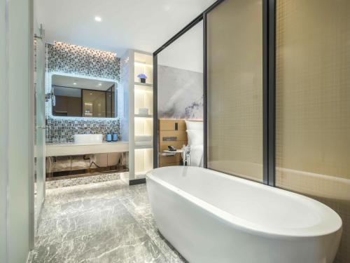 a white bath tub in a bathroom with a sink at Novotel Guangzhou Baiyun Airport in Huadu