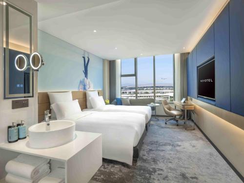 花都にあるNovotel Guangzhou Baiyun Airportの大型ベッドとシンクが備わるホテルルームです。