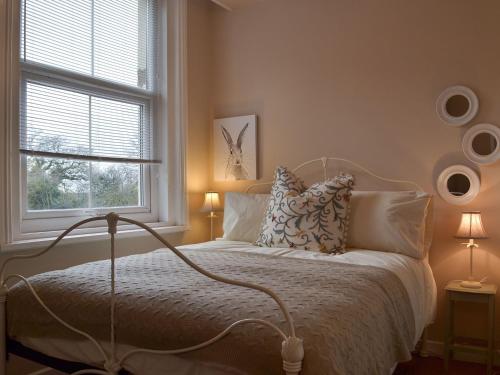 1 dormitorio con cama con almohadas y ventana en Broomleasowe House, en Whittington