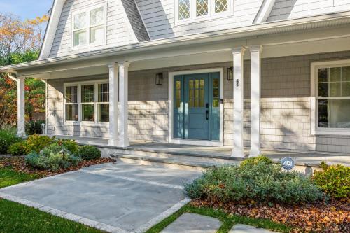 a white house with a blue door and columns at New Construction Modern Luxury Retreat w 6 Beds in Southampton