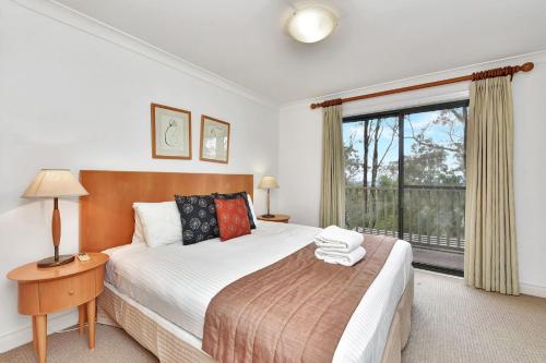 una camera con un grande letto e una finestra di Villa 3br Syrah Villa located within Cypress Lakes Resort a Pokolbin