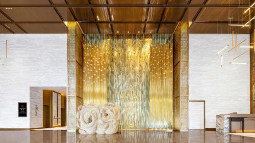 a lobby with a water fountain in a building at HUALUXE Hotels and Resorts Qingdao Licang in Qingdao