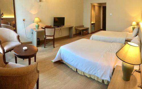 a hotel room with two beds and a table and chairs at Saigon Quy Nhon Hotel in Quy Nhon