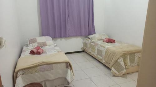 2 camas en una habitación con cortinas moradas en Safira Blessed, en Río de Janeiro