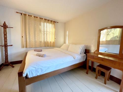 1 dormitorio con cama, espejo y mesa en MTT resort, en Ban Nam Tok Mae Klang