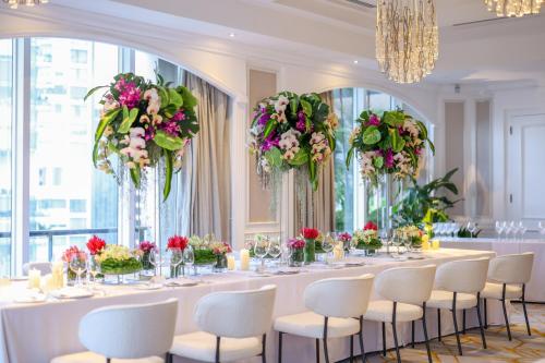 długi stół z krzesłami i kwiatami w pokoju z oknami w obiekcie Four Seasons Hotel Singapore w Singapurze