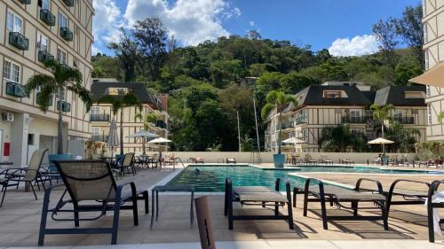 a swimming pool in a building with chairs around it at Estúdios Em Itaipava - Granja Brasil - Conforto e Lazer in Itaipava