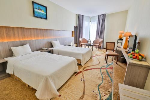a hotel room with two beds and a table at Saigon Quy Nhon Hotel in Quy Nhon