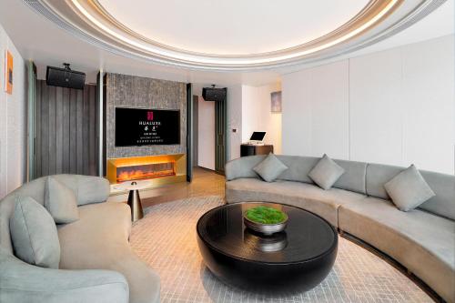 a living room with a couch and a table at HUALUXE Hotels and Resorts Qingdao Licang in Qingdao