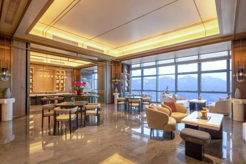 a lobby of a hotel with tables and chairs at HUALUXE Hotels and Resorts Qingdao Licang in Qingdao