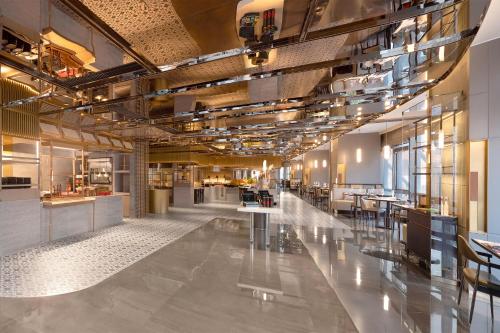 a large lobby with tables and chairs in a building at HUALUXE Hotels and Resorts Qingdao Licang in Qingdao