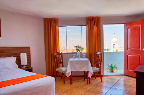 a bedroom with a table and a view of a building at Hotel Plaza San Antonio Arequipa in Arequipa