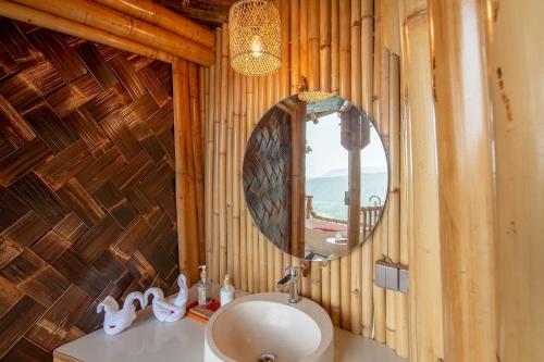 ein Bad mit einem Waschbecken und einem Spiegel in der Unterkunft Dreamy Cliffside Bamboo Villa with Pool and View in Klungkung