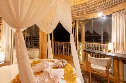 a bedroom with a canopy bed and a balcony at Dreamy Cliffside Bamboo Villa with Pool and View in Klungkung