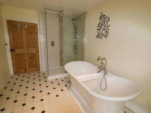 a white bath tub in a bathroom with a shower at The Manor House at Kenwick Lodge in Ellesmere