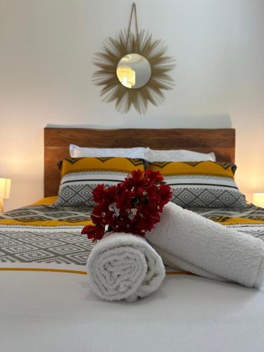 ein Bett mit einem weißen Handtuch und roten Blumen drauf in der Unterkunft Sunset Appart, T2 avec vue mer et plage à 1 km in Le Carbet