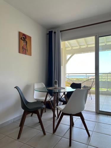 a dining room with a table and chairs and a balcony at Sunset Appart, T2 avec vue mer et plage à 1 km in Le Carbet