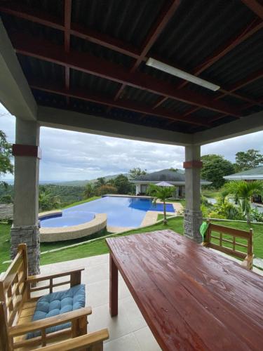 eine Terrasse mit einem Holztisch, Stühlen und einem Pool in der Unterkunft Villa MountainView Guesthouse in Dimiao