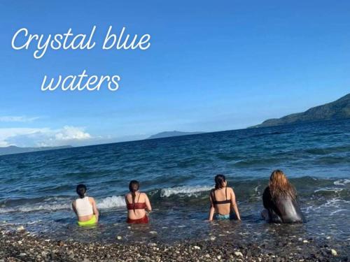 three people sitting in the water at the beach at Tanaw sa Anilao Beach Resort in Mabini