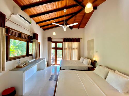 a bedroom with two beds and a ceiling at Mansala Safari House in Udawalawe