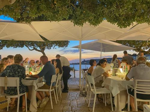 een groep mensen die aan tafels onder parasols zitten bij Cà Mì Apartment in Galatone