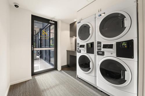 a laundry room with three washer and dryer at And Apartments in Canberra