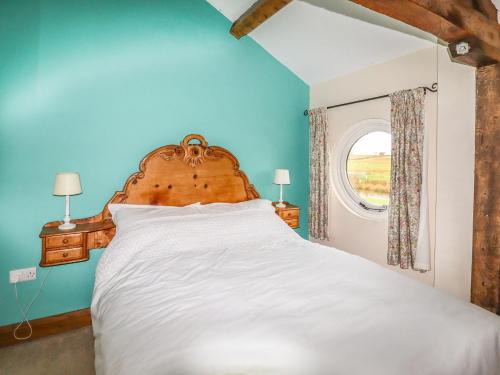 a bedroom with a large white bed with a window at The Barn in Ellesmere