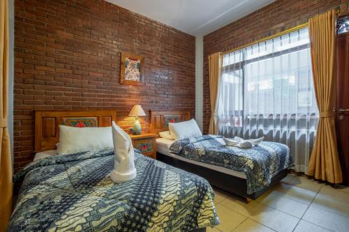 a bedroom with two beds and a brick wall at Sekararum Butik Syariah Guesthouse in Bandung