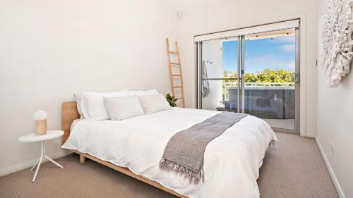 Un dormitorio blanco con una cama y una ventana grande. en Coast Fingal Bay, en Fingal Bay