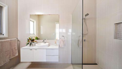 Un baño blanco con lavabo y ducha. en Coast Fingal Bay, en Fingal Bay