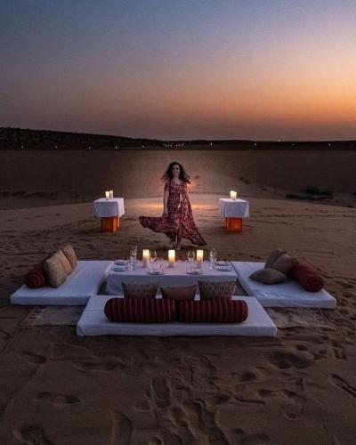a woman is sitting on the beach with candles at Excellent Desert Safari camp in Sām