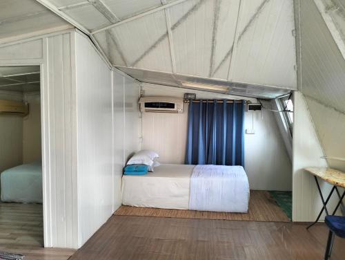 a bedroom with a bed and a blue curtain at Leaf Boat House in Miri