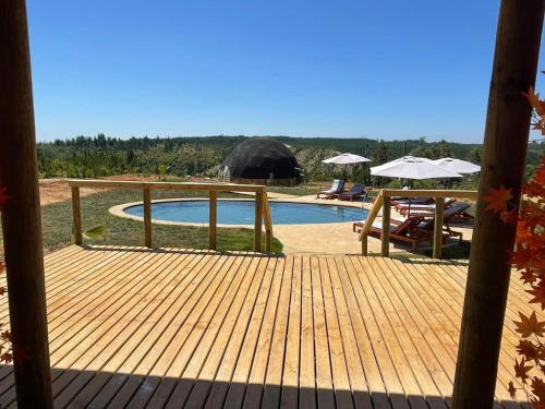 a wooden deck with a pool and umbrellas at DOMO Y SPA INFINITO in Catillo