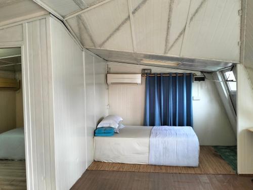 a bedroom with a bed with a blue curtain at Leaf Boat House in Miri