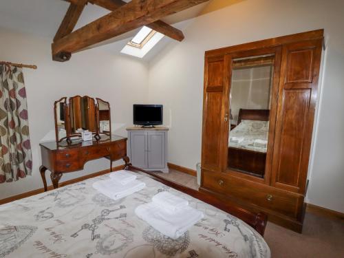 a bedroom with a bed and a dresser and a television at The Oaks in Ellesmere