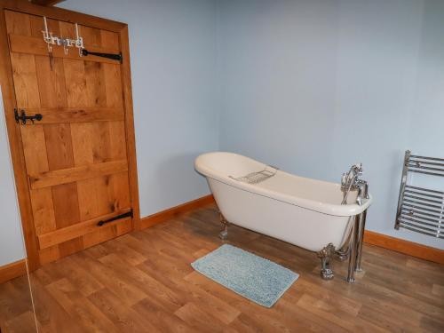 a bath tub in a room with a wooden door at The Oaks in Ellesmere