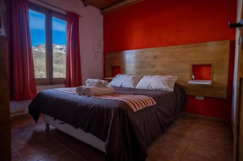 a bedroom with a bed with red walls and a window at Los Molles Complejo Turistico in Los Molles