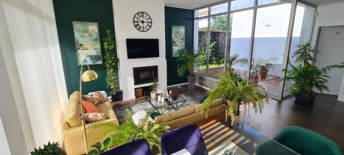 a living room with couches and plants and a clock at Magnolia Residence - central to explore the island in Ribeira Grande